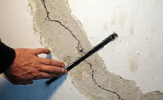 A wall with a large crack is being inspected by a professional in Jacksonville, FL